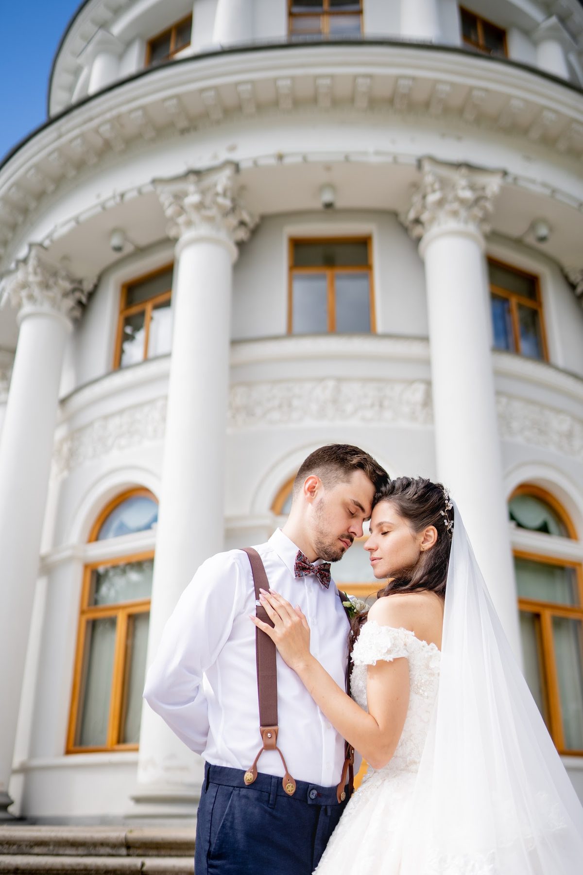 Couple embracing by a white building